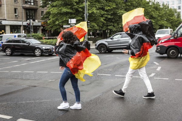 DEU Germany Germany Berlin Two tourists with rain capes in the colours of Germany while sight