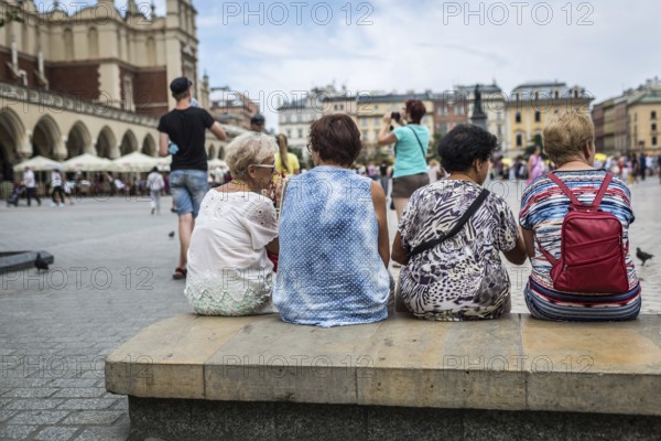 POL Poland Poland Krakow Krakow Tourists with colourful blouses sit on the market square in the Old