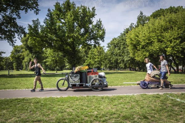 DEU Germany Germany Berlin Young men transporting technology for an event through Volkspark