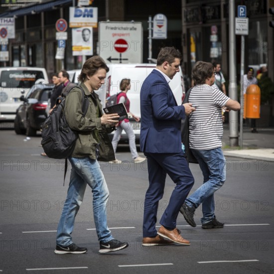 DEU Germany Germany Berlin A young man walks along Friedrichsstrasse reading while another looks at