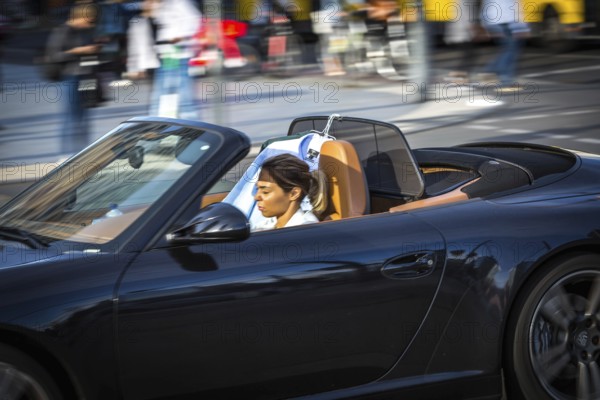 DEU Germany Germany Berlin A woman is dazzled by the sun as she drives her convertible across