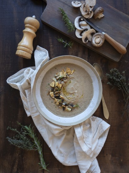 Mushroom soup with rosemary, thyme, garlic croutons, and raw mushrooms on a dark wood background