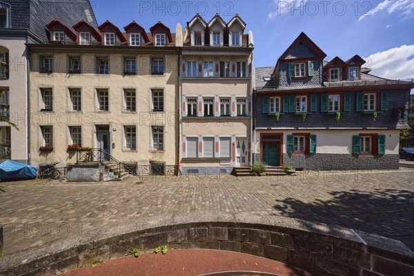 Historic buildings, houses, downpipes, façade with windows, dormers, stairs and doors, paving stone