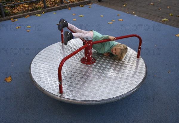 Outdoor shot, little girl, child, 4 years, blonde, playing, gymnastics on carousel, children's