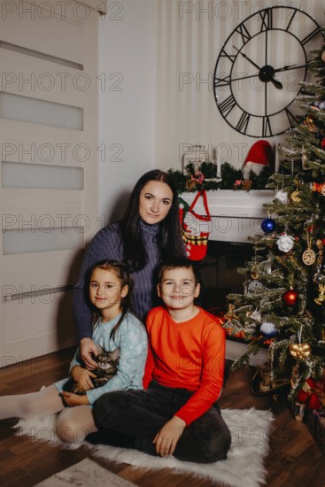 Family group portrait showing a mother, children, and kitten in a festive christmas home setting