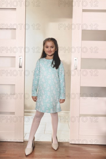 Young girl standing in a doorway wearing high heels, imagining growing up.Belarus