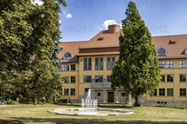 Yellow historic building with fountain and trees in the foreground, The old town of Arnstadt in