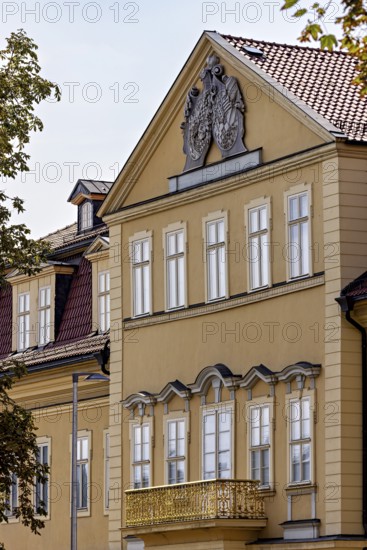 Detailed view of a baroque building with yellow façade, decorated pediment and windows, the façade