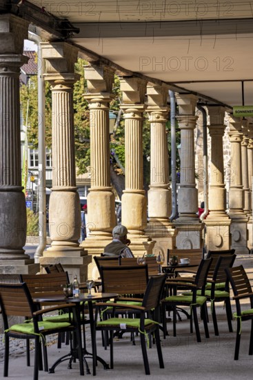 Historic outdoor café under pillars with green chairs and a quiet atmosphere in the city, arcades
