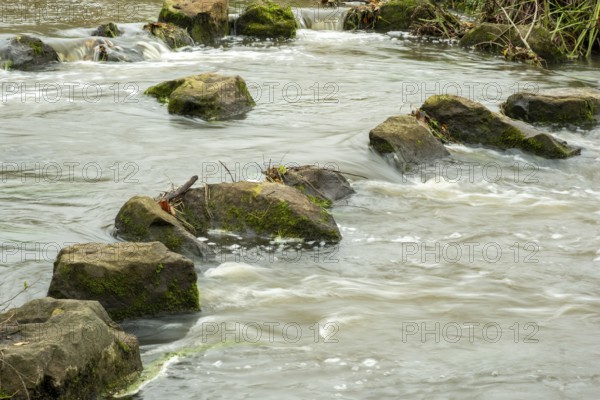 Borken-Hoxfeld, NRW, Germany, Rocks are partially submerged in flowing water, forming a natural