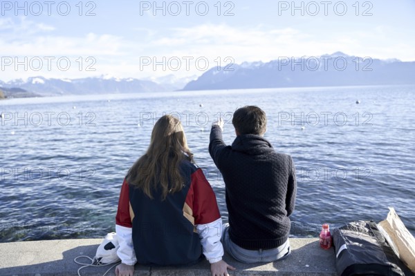 NO MODEL RELEASE, unrecogniseable couple pointing at mountains Les Cornettes de Bise behind Lake