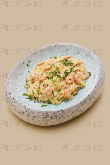 A creamy dish of risoni pasta combined with tender shrimp and fresh herbs is presented in an