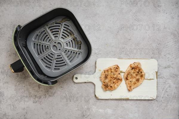 Two perfectly cooked pork sirloin chops rest on a cutting board beside an air fryer basket. The