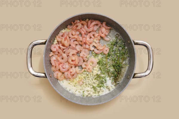Shrimps and herbs sizzle in a pan, blending with chopped garlic, ginger and olive oil. Process of