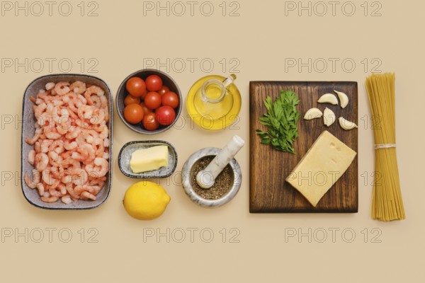 Shrimps, cherry tomatoes, garlic, and parsley lie neatly on a table along with lemon, butter, olive