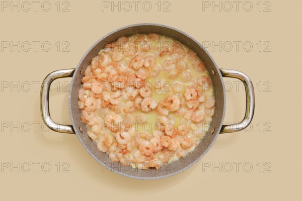 A skillet is filled with juicy, cooked shrimp in a creamy garlic sauce, ready to be tossed with