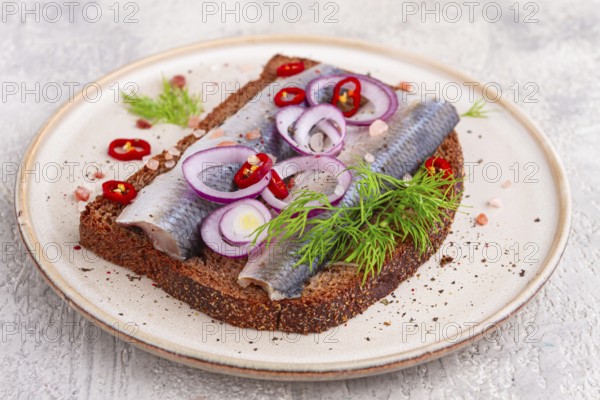 Sandwiches, Herring fish, on dark rye bread, sprinkled with onion, chili pepper and herbs, on a