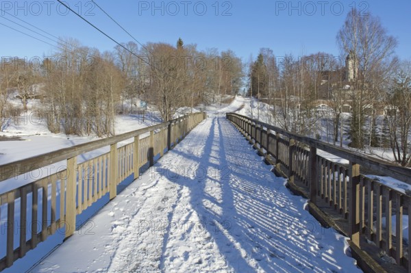 Old wooden walk bridge over river Koskenkylänjoki on a sunny winter day with snow covering the