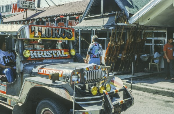 Jeepney minibus in front of a restaurant with skewered suckling pig, Lechon, Manila in 1995,
