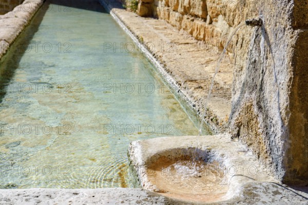 Ronda, malaga, spain Fresh, clear water flowing from an old stone spout into a historic rustic