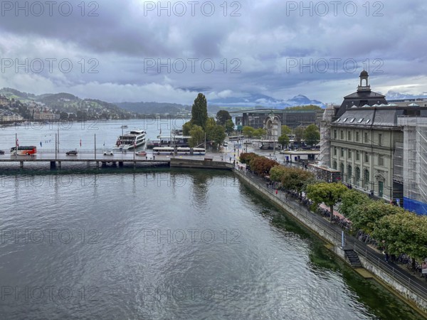 View of waterfront with boats and mountains in the background under cloudy sky, Lucerne,