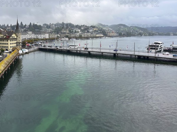 Harbour view with boats, buildings and hills in the background under cloudy sky, Lucerne,