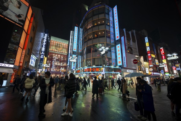 Busy pedestrian zone with many shopping centers and stores, illuminated with lots of neon signs at