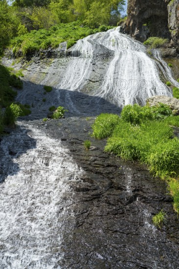 A steep stream flows through rocks and green plants, in the heart of a natural landscape, Jermuk