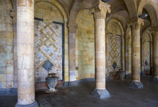 Column with mosaic walls and reliefs surrounded by stone arches that create an ancient atmosphere,