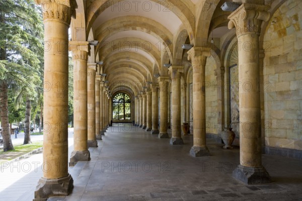 Long, minimalist portico with symmetrical stone arches in a cool interior steeped in history,