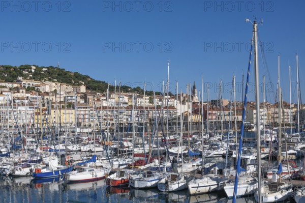 Densely packed sailboats and yachts with numerous masts in the port of Sete, with the densely built