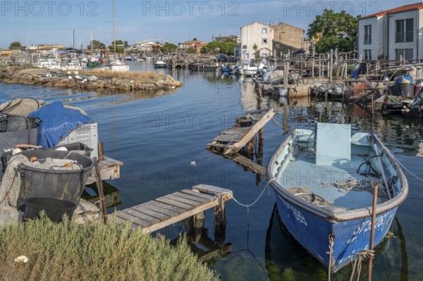 A blue fishing boat is moored on dilapidated wooden walkways in a small harbor basin of La Pointe