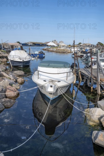 A white moored motor boat with reflection in the calm water of a small harbor of the traditional