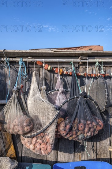 Close-up of various fishing nets and fish traps with red floats and shackles suspended for drying