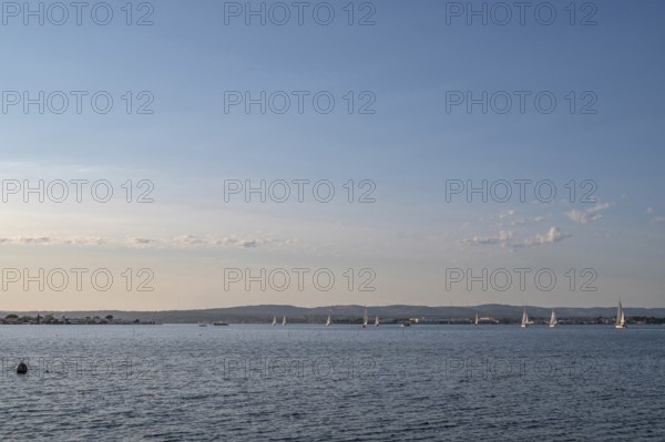 Wide-angle landscape view of Etang de Thau with several sailboats on the water sailing towards the
