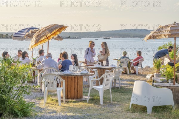 Summer scene on the terrace of the Guinguette A la bonne Franquette with guests sitting at tables