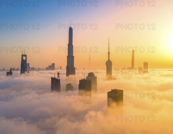 City scape emerging from a dense enveloping fog in sunrise and skyscrapers piercing the haze, big