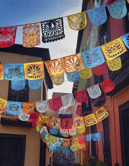 A vibrant display of colorful papel picado decorations hanging across a narrow Mexican street,