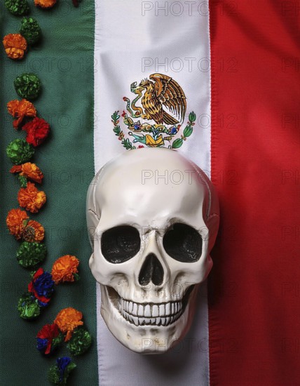 A skull placed on the Mexican flag, accompanied by a colorful marigold garland, symbolizing the Day