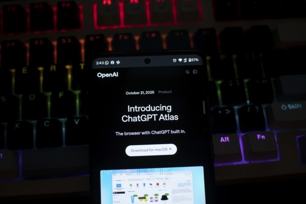 A smartphone displaying ChatGPT Atlas against a colorful, illuminated keyboard