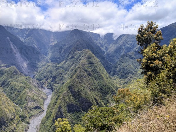 Breathtaking view of mountainous landscape with a river cutting through under a partly cloudy sky,