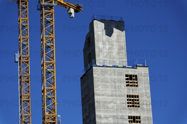 Yellow cranes on construction site of timber building Kaj 16 with hybrid concrete frames, sunny