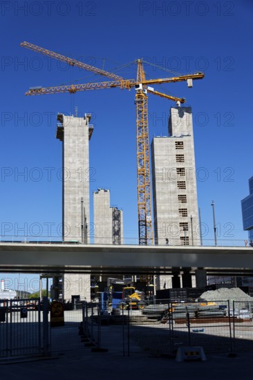 Yellow cranes on construction site of timber building Kaj 16 with hybrid concrete frames, sunny