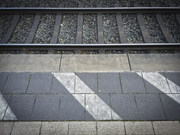 Station tracks with gravel bed, adjacent asphalt and eye-catching strip markings, platform in 27798