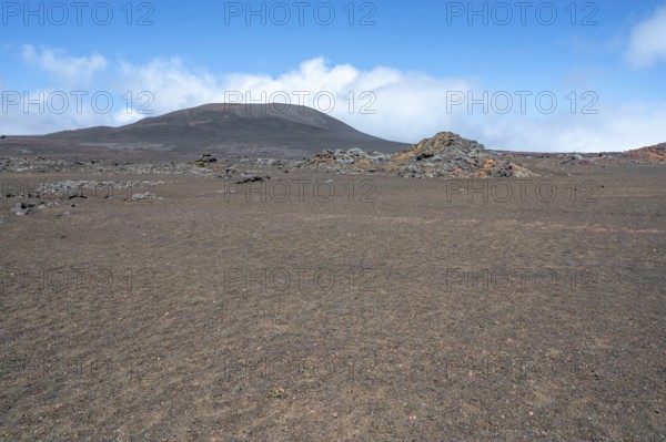 The Route du Volcan crosses the vast, rust-red volcanic desert of the Plaine des Sables, whose