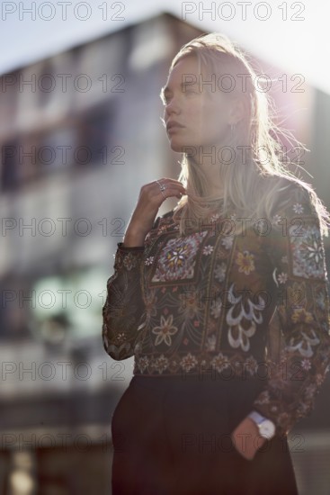 Elegant designer woman in sunlight in front of futuristic modern architecture house, apartment