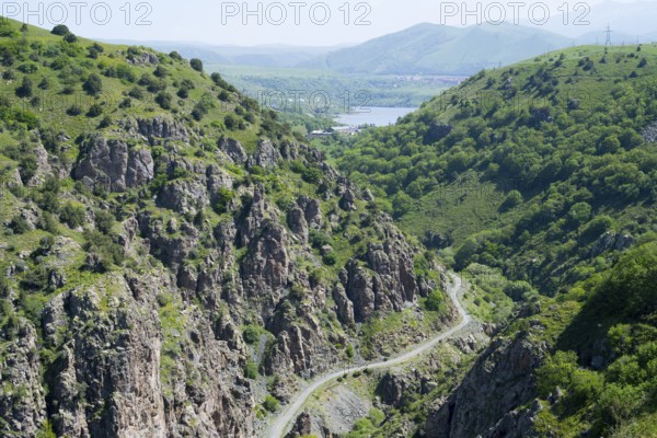 A green mountain landscape with rocks crossed by a road with a wide view of the valley, canyon of