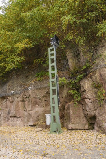 Green signal tower in front of rocky embankment with trees and safety net, Signalbau an der Hermann