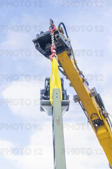 A yellow crane lifts a metal structure, blue sky in the background, signalling at the Hermann