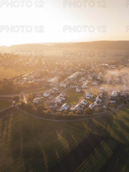 Village and fields in morning fog with warm shades of sunrise light, Calw Stammheim, Black Forest,